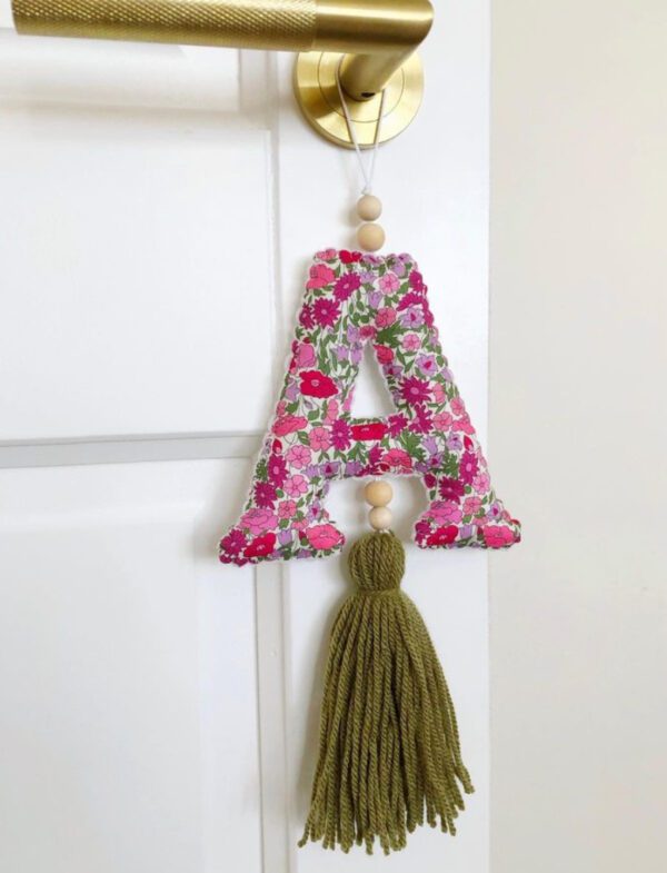A letter hanging on the wall with a tassel.