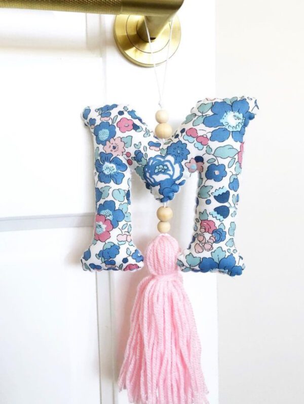 A letter hanging on the wall with a tassel.